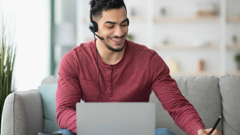 Homem fazendo anotações enquanto utiliza VoIP em home office